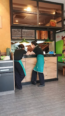 The image shows an indoor setting of a restaurant or cafe where two staff members are interacting at the counter.