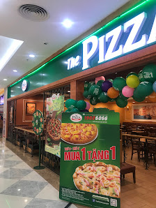 The image depicts the interior of 'The Pizza' restaurant located in Thao Dien, Saigon. It features a green neon sign with 'The Pizza' branding, colorf