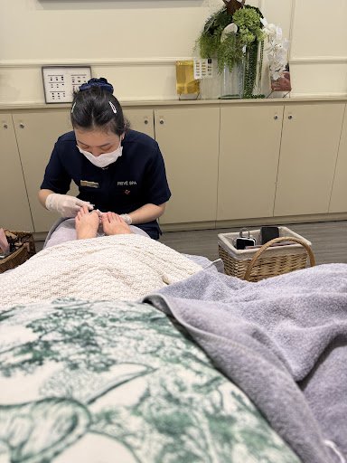 The image depicts an indoor setting where a person is receiving a foot massage at what appears to be a spa or wellness center.