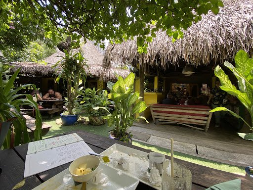 The image depicts an outdoor seating area of a tropical-themed restaurant or bar in Thao Dien, Saigon. The setting is lush with greenery and features 
