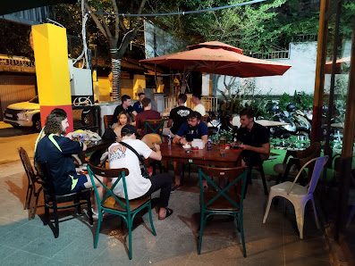 A group of people are seated at a table in an outdoor dining area during the evening hours.