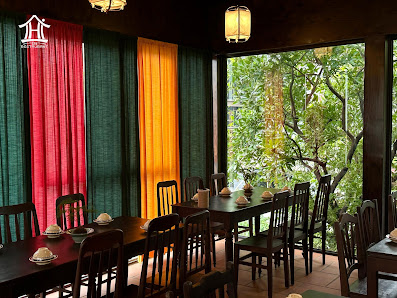 The image shows an interior dining area of a restaurant or cafe in Thao Dien, Saigon. The space features wooden chairs and tables set with white plate