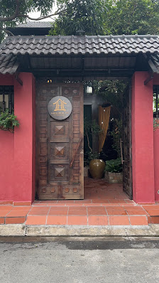 The image shows an exterior view of a restaurant or cafe located in Thao Dien, Saigon. The entrance features red brick walls and a wooden door with de