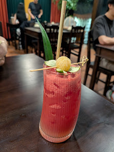 A close-up of a cocktail served in a glass on a wooden table at an indoor venue.