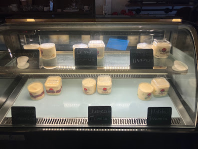 A display case in a venue showcasing various dessert containers labeled with names such as 'Crème Brûlée', 'Mango Panna Cotta', and others.