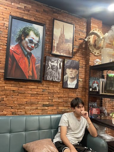 The image shows an interior space featuring a brick wall adorned with framed pictures of various characters and scenes from popular culture. A young p
