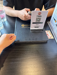 A close-up of a dark wooden table in a restaurant in Thao Dien, Saigon. On the table, there's a black menu stand with a white card displaying a QR cod