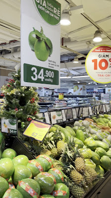 Interior of a supermarket in Thao Dien, Saigon, showcasing a fruit section with various produce including green apples, pineapples, and other tropical