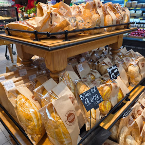 The image depicts a bakery section within a supermarket in Thao Dien, Saigon. Multiple shelves display various packaged breads and pastries, including