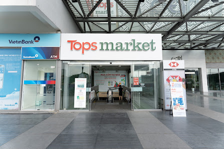 The image depicts the entrance of Tops market, a retail store located within a modern shopping mall in Thao Dien, Saigon. To the left of Tops market i