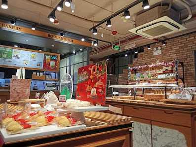 The image shows an interior view of a bakery and café in Thao Dien, Saigon. The space is well-lit with multiple light sources including track lighting