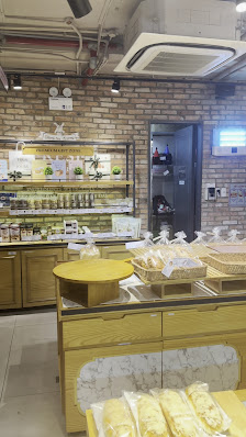The image shows an interior view of a bakery or café counter area featuring various baked goods and desserts displayed on shelves and counters.