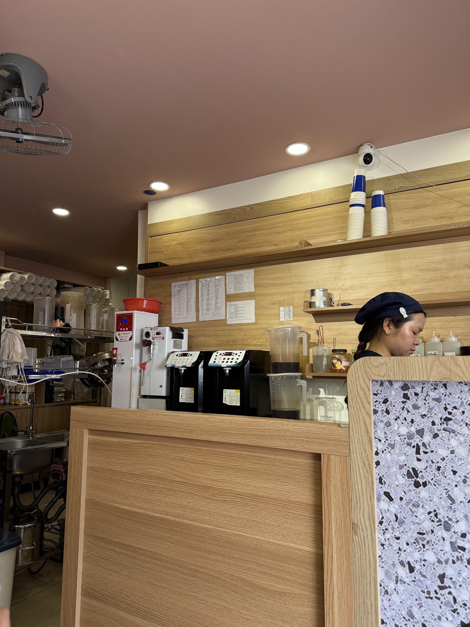 The image shows an interior view of a coffee shop or cafe in Thao Dien, Saigon. The counter area is equipped with various appliances such as coffee ma
