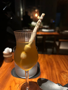 A close-up shot of a cocktail glass containing an amber-colored liquid and two spherical objects on the rim.