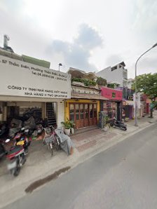 The image shows a street view of an exterior scene in Thao Dien, Saigon with various shops and motorcycles parked on the side.