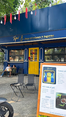 The image shows an exterior view of a restaurant named '147 B House of Croissants & Baguettes'. It has blue and yellow colors with red accents, includ