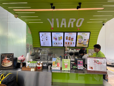 The image shows an interior view of a beverage shop named 'VIARO'. The counter is visible with various drink options displayed on digital menus above