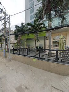 The image shows an outdoor seating area of a restaurant or cafe in Thao Dien, Saigon. There are green plants and palm trees visible behind the railing