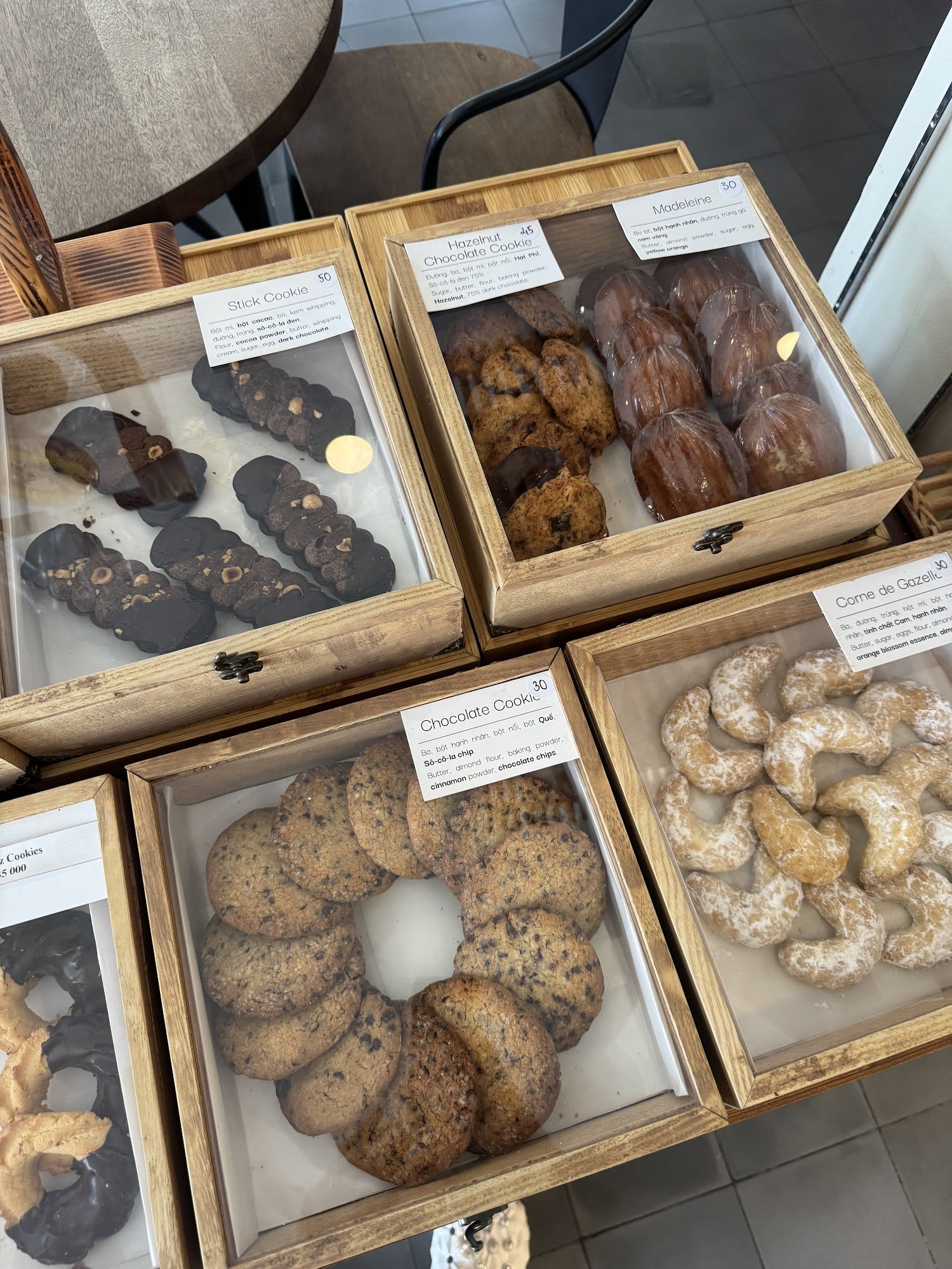 A display of various baked goods in wooden boxes on a table at Thao Dien, Saigon.