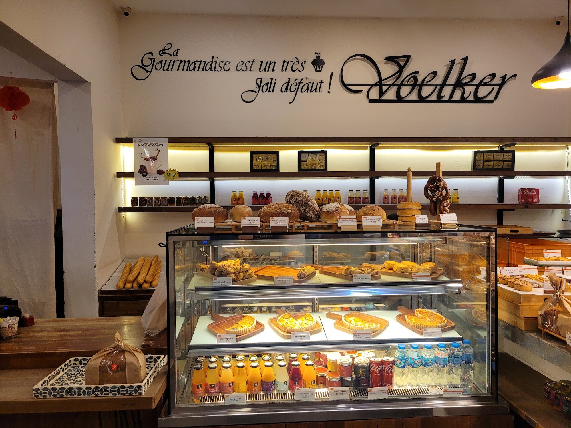 The image shows an interior view of a bakery or café named 'Joelker'. The display case is filled with various baked goods such as pastries, breads, an