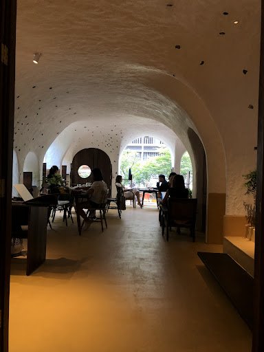 The image depicts an interior view of a modern café or restaurant in Thao Dien, Saigon. The space features arched ceilings with exposed beams and is i