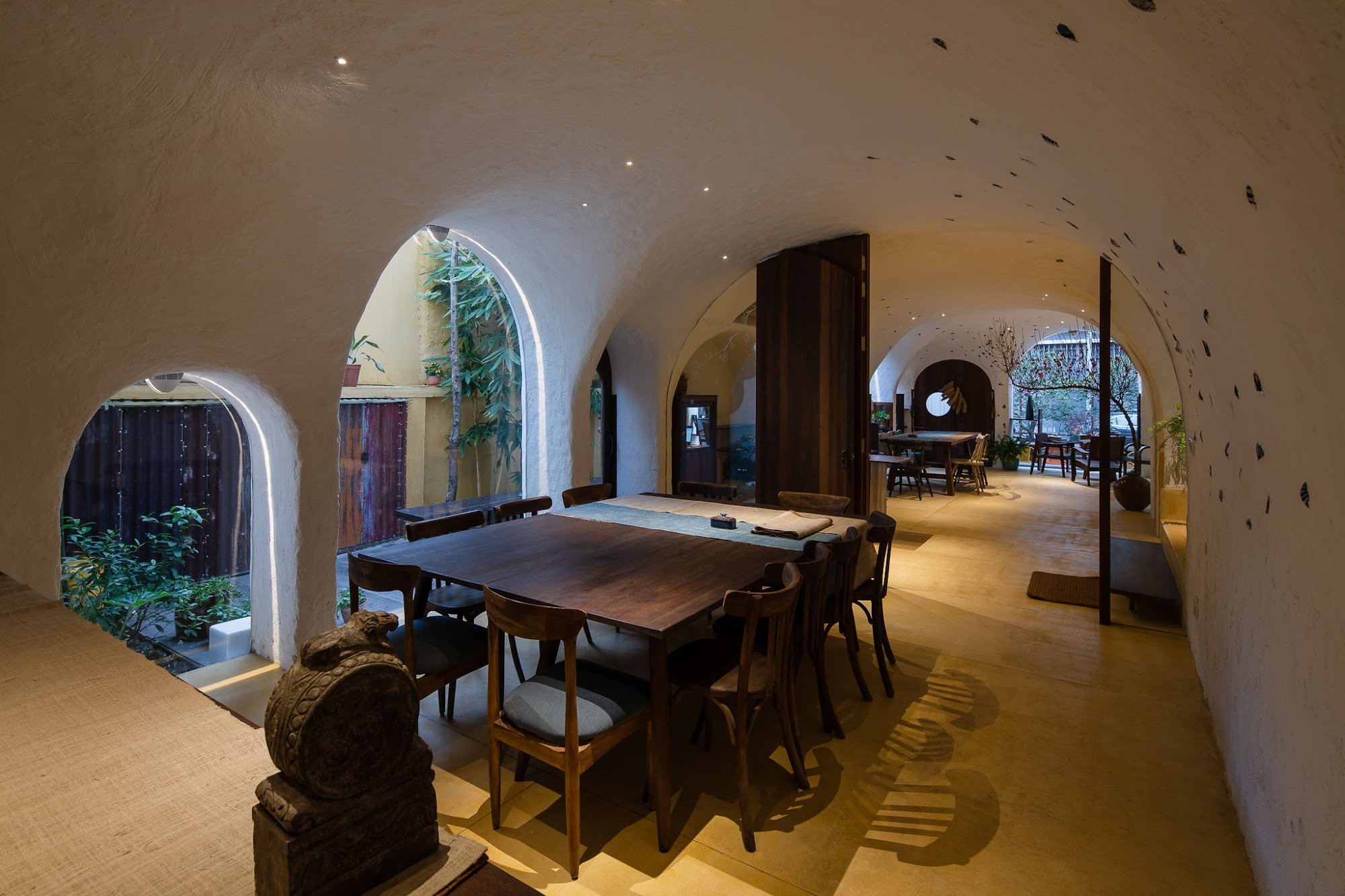 The image depicts an interior space that appears to be a dining area within a modern building with curved architecture and natural lighting coming thr