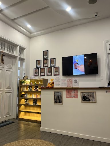 The image depicts an interior space of a venue in Thao Dien, Saigon. It features a white wall with a mounted flat-screen TV displaying a video, a grid