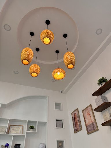 The image depicts the interior of a modern venue in Thao Dien, Saigon. It features a circular ceiling with five woven pendant lights emitting warm yel