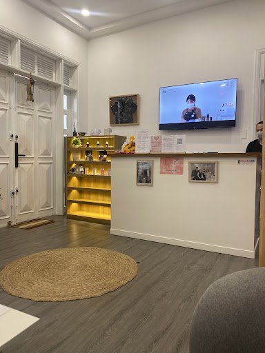 The image depicts an interior space of a venue in Thao Dien, Saigon. It features a white reception counter with framed pictures and a TV mounted above