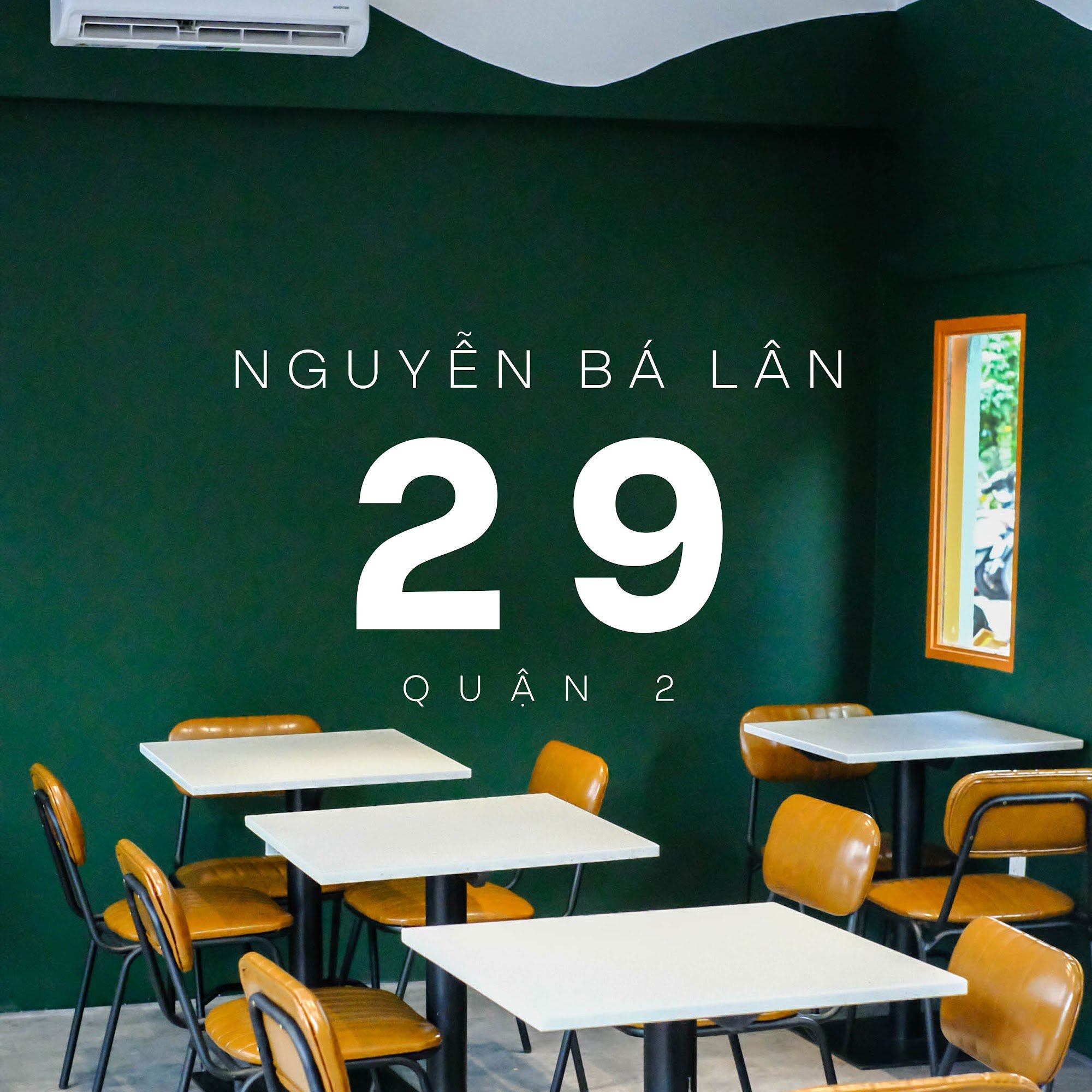 The image shows an interior space of a venue named 'NGUYÊN BÀ LAwards' with the number '29 QUAN 2'. The room has green walls, white tables and chairs 