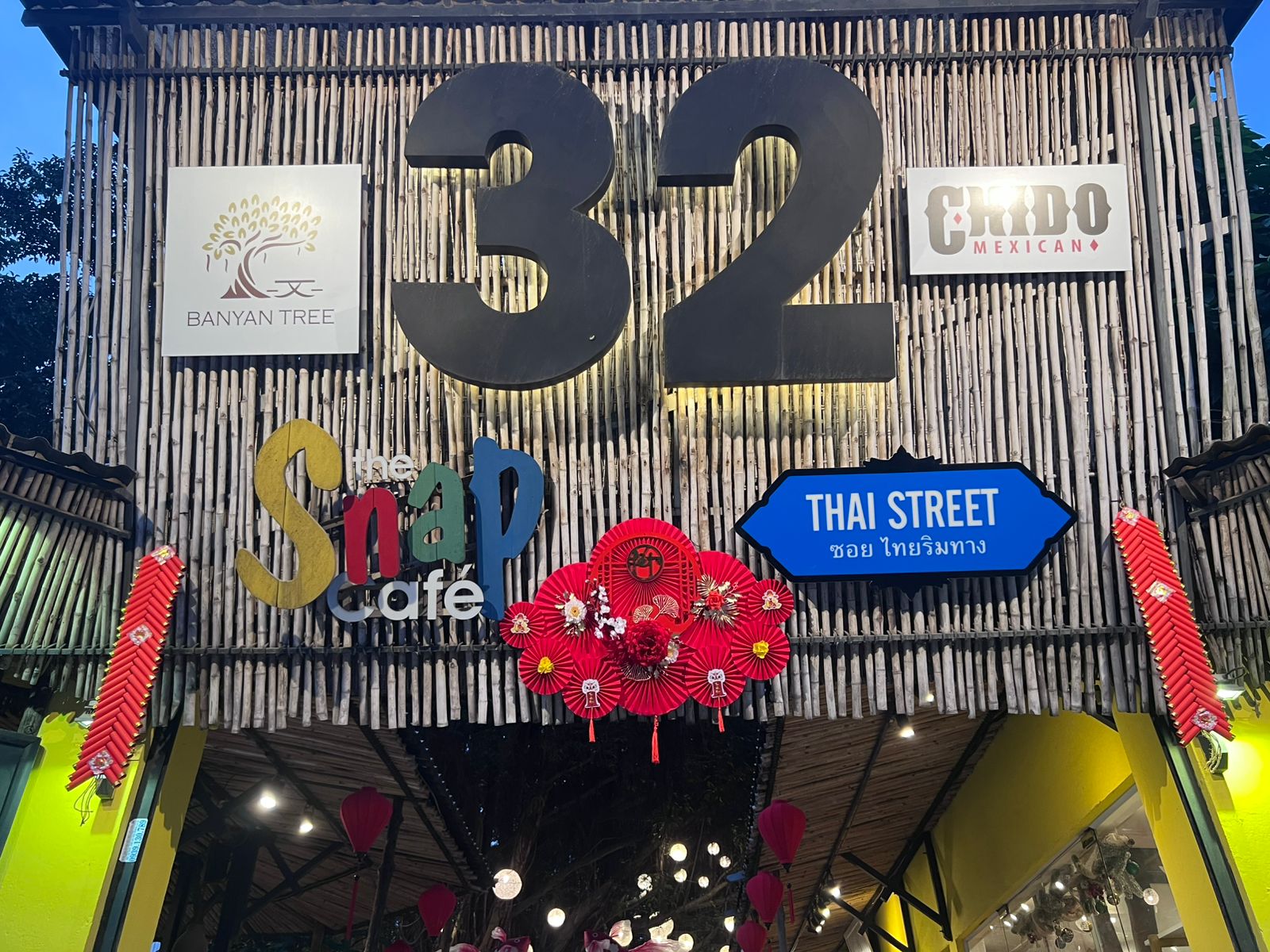 The image depicts the exterior facade of a multi-venue complex in Thao Dien, Saigon. The structure features a bamboo wall with large black "32" numera