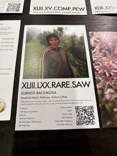 The image displays a menu card for 'SUKKOT RACEMOSA' coffee from XLIII.LXX.RARE.SAW. It features a photograph of a person in a rural setting, details 