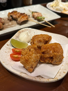 The image shows a plate of golden-brown fried food items accompanied by lime wedges and green chutney on the side, with additional dishes in the backg