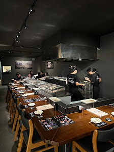 The image depicts an interior view of a modern restaurant or dining establishment featuring dark walls and contemporary decor. A long table with multi