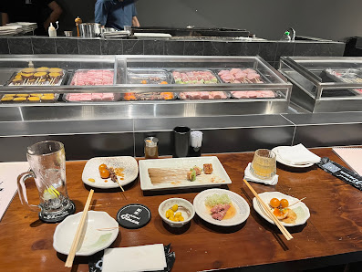 The image shows a dining area in Thao Dien, Saigon featuring an assortment of dishes and desserts on display at the counter with various condiments an