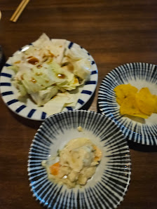 A plate of cabbage with sauce, a bowl of potato chips, and another dish possibly containing chicken or tofu
