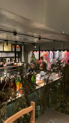 The image shows an indoor setting of a restaurant or bar in Thao Dien, Saigon with patrons seated at the counter and various bottles on display.