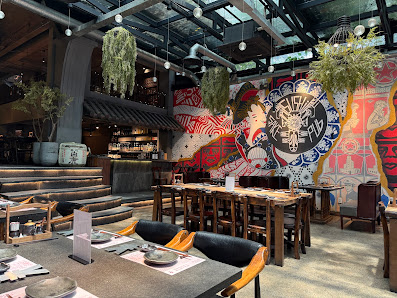 The interior of a modern restaurant featuring an eclectic mix of decor elements such as hanging plants, exposed brickwork, and vibrant wall art with A