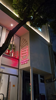 The exterior of a modern restaurant named 'Taiwanese Kitchen' illuminated at night with neon signage.